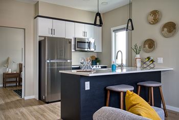 A kitchen with a stainless steel refrigerator and a dark blue counter.